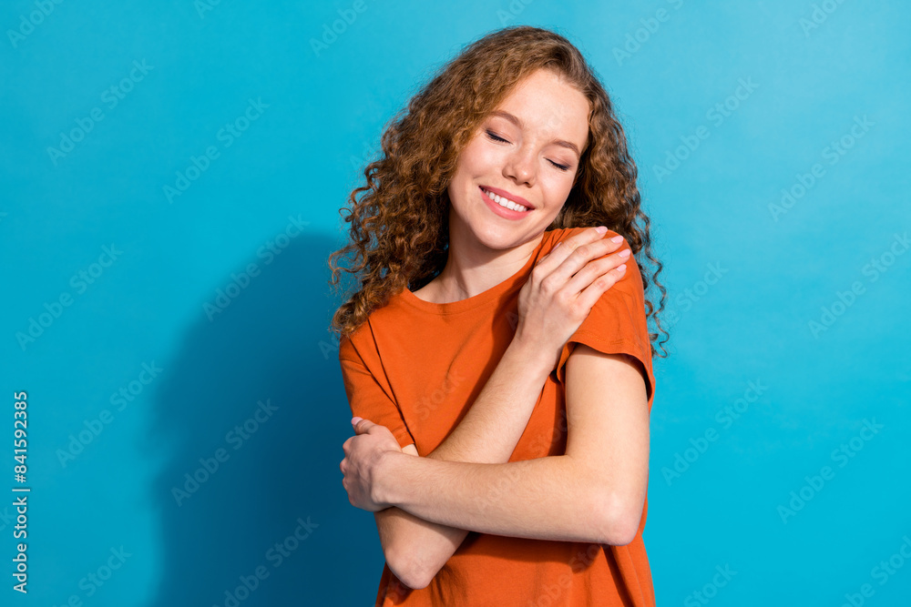 Wall mural Photo of positive smiling girl hug herself enjoy isolated blue color background