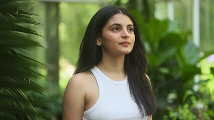 Portrait of calm young indian woman looking ahead and exhaling fresh air taking deep breath and reducing stress after hard day at park Serene dark haired female resting for peaceful mind outdoors