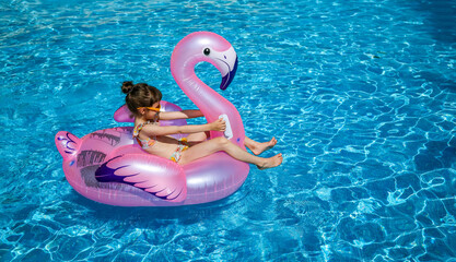 Little girl in a pink flamingo pool float, emphasizing summer activities and kids' leisure products