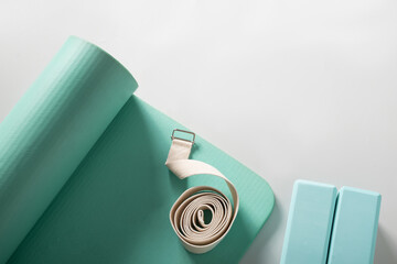 Green mat, two yoga blocks and belt on gray background. Top view. Yoga practice, stretching and...