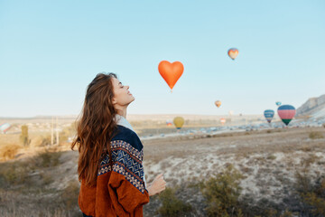 Woman admiring hot air balloons in cappadocia with heart shaped balloon in hand