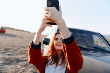 Woman taking a selfie in front of vintage car on scenic field