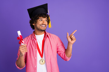 Portrait of nice young man mortarboard diploma direct finger empty space wear pink shirt isolated...