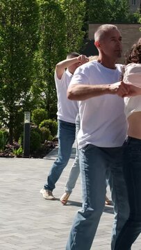 Guy and girl dance beautifully bachata in city center Kharkiv, Ukraine Several couples in jeans and T-shirts dance in nature
