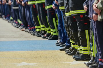 A group of firefighters lined up, saluting the flag, applauding in solidarity, and gearing up for...