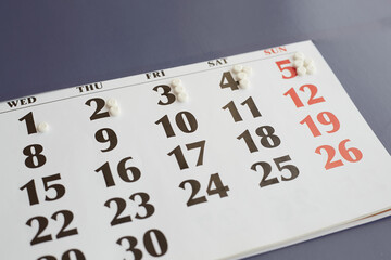 Obraz premium Tagged white pills on calendar closeup, increasing dose of medication by day, increasing dose of medication, daily medication, increasing dose of medication