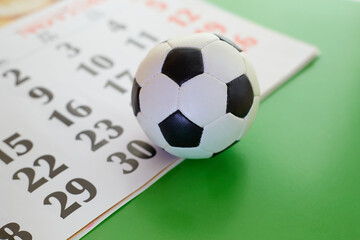 Soccer ball on calendar and green background closeup, soccer ball closeup, sports betting, sports...