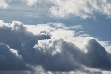 White sunlight on gray-blue cumulus clouds in the sky, changeable weather, formation of clouds in...