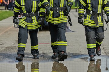 A team of confident and accomplished firefighters strides purposefully in their uniforms, exuding...