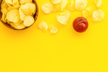 Wooden bowl of crispy potato chips, top view. Fast food and snack background