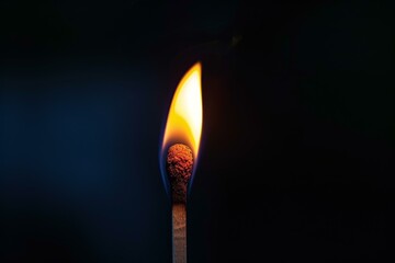 Close-up of a single burning matchstick with an orange and blue flame, isolated on a dark backdrop