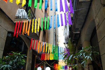 Festive ribbon of multicolored rainbow flags on the urban background. Celebration party, holiday fair, festival decorations. Gay pride symbol.