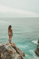 Portrait of adult unknown woman stand on a rock and looking at the sea