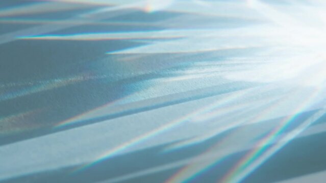 Sharp Beams from Lens Edges. Loop. The optical lens system creates a series of bright, changing geometric highlights on a light surface