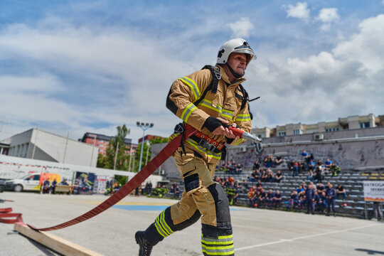 In a dynamic display of synchronized teamwork, firefighters hustle to carry, connect, and deploy firefighting hoses with precision, showcasing their intensive training and readiness for challenging