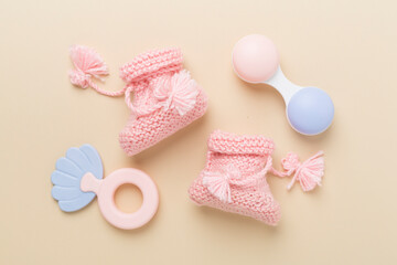 Pink baby booties and rattles on color background, top view
