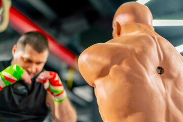 close up in a boxing fight club senior muscular trainer in a black T-shirt and with multi-colored...