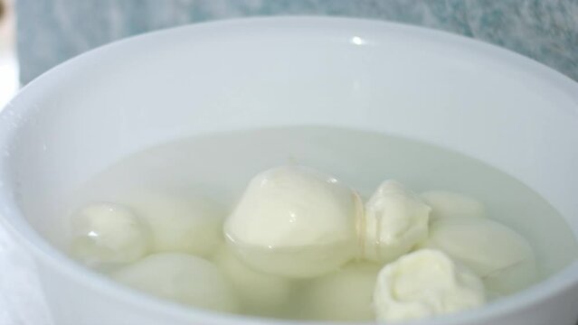 A wheel of Kacha Kavala cheese in a special brine in water exhibition preparation sale. seller takes it out