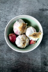 White bowl with heads of raw garlic