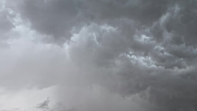 The gray clouds in the overcast sky are occasionally illuminated by flashes of lightning