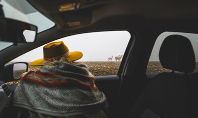 A man wearing a yellow hat is sitting in a car looking out the window, tourist in the peruvian andes