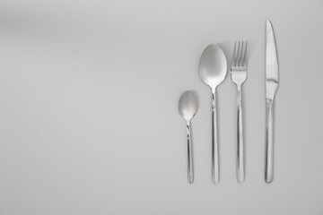 Stylish silver cutlery set on gray background, flat lay. Space for text