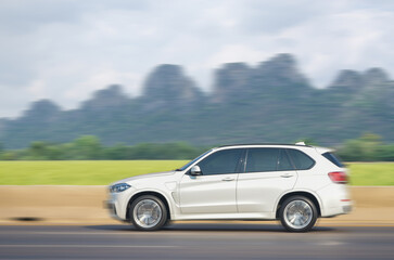 White car running at speed in Thailand's mountain landscape roads at daylight