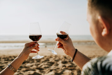 a guy and a girl drink wine on the beach