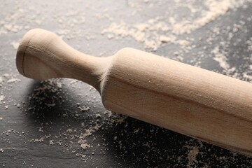 Scattered flour and rolling pin on dark textured table, closeup