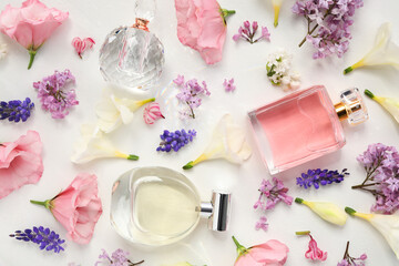 Luxury perfumes and floral decor on white background, flat lay