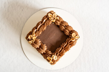 diamond shaped cake with room for an inscription. Cake mocap. Chocolate cake with buttercream and nuts on white background on the center of the frame, flatlay. minimalist cake design.  