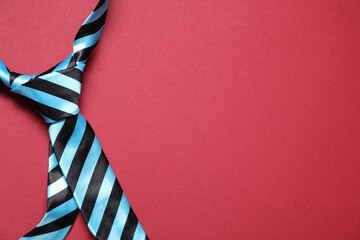 Stylish striped necktie on red background, top view. Space for text