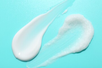 Samples of face cream on light blue background, top view