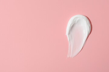 Sample of face cream on pink background, top view. Space for text
