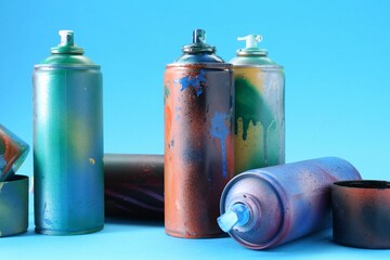 Many spray paint cans and caps on light blue background