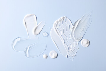 Fototapeta premium Samples of face cream on light blue background, top view
