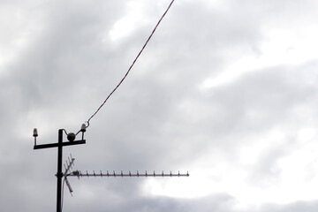 Obraz premium Uhf antenna for catching television broadcasts against a grey sky background. Old gray antenna against a vintage sky backdrop