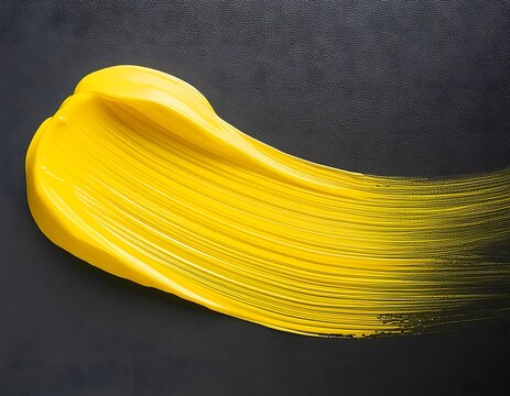 Brushstroke of deep yellow tempera or acrylic paint on a grey background. 