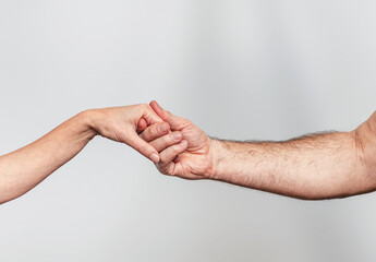 Man hand carefully supports woman hand. Gray background. Harmonious relationship symbol.