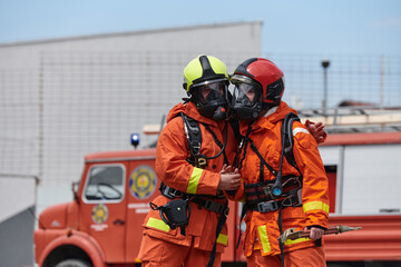 A unified team of firefighters, adorned in their uniforms, engages in a heartfelt celebration marked by triumphant salutes and cheers, embodying the joy and gratitude following the successful