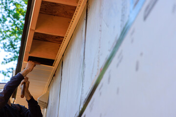 Vinyl white uPVC soffit board below facia roof installed along roofline of house.