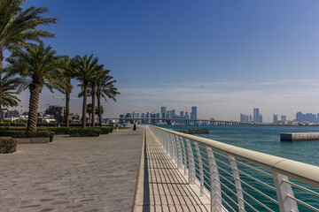 Abu Dhabi cityscape with palm trees and promenade. Landscape view of Abu Dhabi with skyscrapers on...