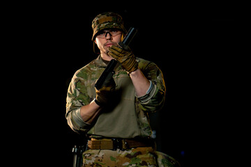 at a professional shooting range a military weapons trainer standing screws on a silencer
