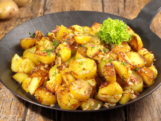 Classic Roasted Potatoes in a Pan with Bacon and Onions on wooden Background