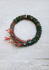 Large Christmas wreath with fir branches, toys and decorations on the wall of the house on the street. Festive, New Year handmade composition. Lviv, Ukraine.