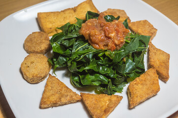 Indonesian traditional food: Boiled Japanese papaya leaves, with tomato sauce, with tempeh and tofu (Indonesian fermented soy patties)