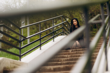 Smiling woman in sportswear sitting on stairs outdoors