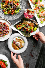 An assortment of gourmet dishes displayed on a dark, textured surface, showcasing vibrant colors and diverse textures.