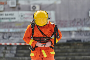 A firefighter dons the essential components of their professional gear, embodying resilience, commitment, and readiness as they gear up for a hazardous firefighting mission, a testament to their