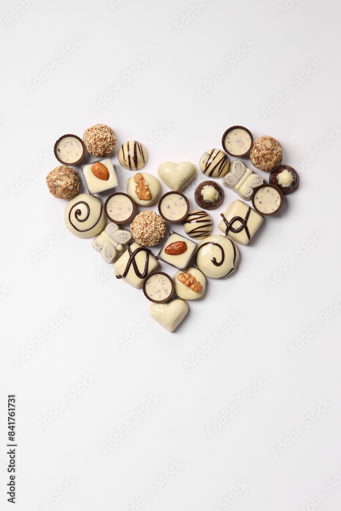 Poster Heart made with delicious chocolate candies on white background, top view